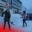 Notdienst: Inhaber bricht in eigene Apotheken ein KI-Montage: Ein Apotheker schippt Schnee vor seiner Apotheke, während Kundschaft an der Feuertonne wartet und eine PKA auf Skiern vorbeifährt