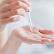 Wirkstoffduo Vitamin C/A: Was steckt hinter dem Trend? Foto: Eine Person tropft mit einer Pipette Flüssigkeit auf ihre Hand.