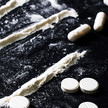 Drogentote: Oft Benzos oder Opioide im Spiel Foto: Weiße Tabletten, Kapseln und Pulverlines auf einem schwarzen Untergrund.