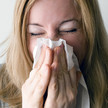 Krankmeldungen bei Jüngeren häufiger – aber kürzer Symbolbild: Frau putzt sich die Nase