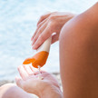 Sonnenschutz: Deshalb reicht LSF 30 nicht Foto: Eine Person gibt sich Sonnencreme am Strand auf die Hand.