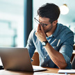 Bore-out: Stress durch Unterforderung Foto: Ein Mann sitzt vor einem Laptop in einer Büroumgebung.