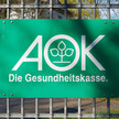 AOK: Das steht im neuen Inko-Vertrag Ein Schild der AOK Krankenkasse hängt an einem Zaun.