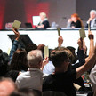 Abgrenzung zum Versandhandel: DAT-Antrag abgeschmettert Delegierte halten ihre Zettel hoch