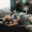 Apotheker nehmen Influencer ins Visier Foto: Eine jugendliche Person liegt auf ihrem Bett und schaut auf ihr Smartphone