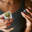 Cannabis: Mehr Menschen wegen Konsumfolgen in Behandlung Symbolbild: Frau öffnet Gläschen mit Cannabisblüten